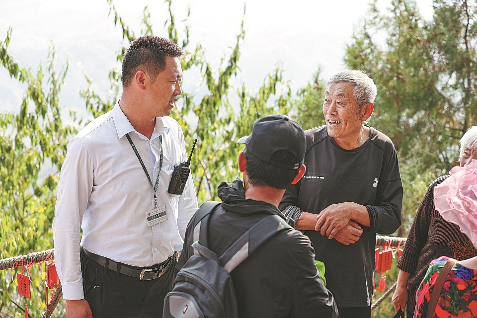 Чжоу Вэньцзюнь (слева), охранник на участке Сыматай Великой Китайской стены, делится с посетителями своими знаниями об этой достопримечательности.
